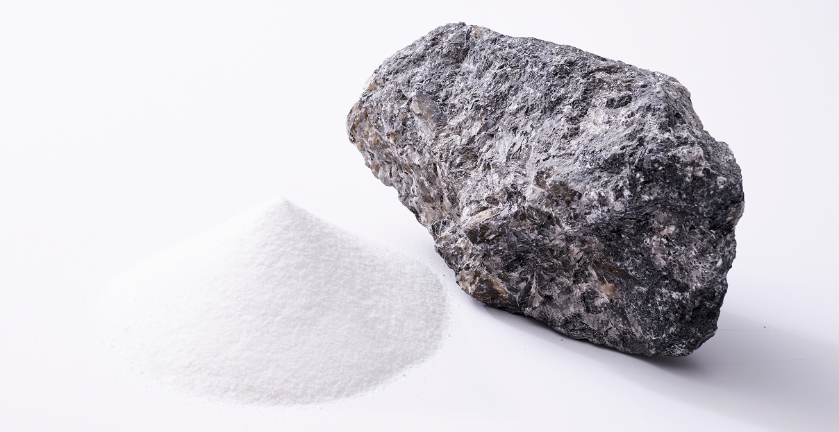 A person working in a mine, wearing a yellow vest and white helmet